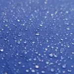 Raindrops on a blue umbrella during wet weather